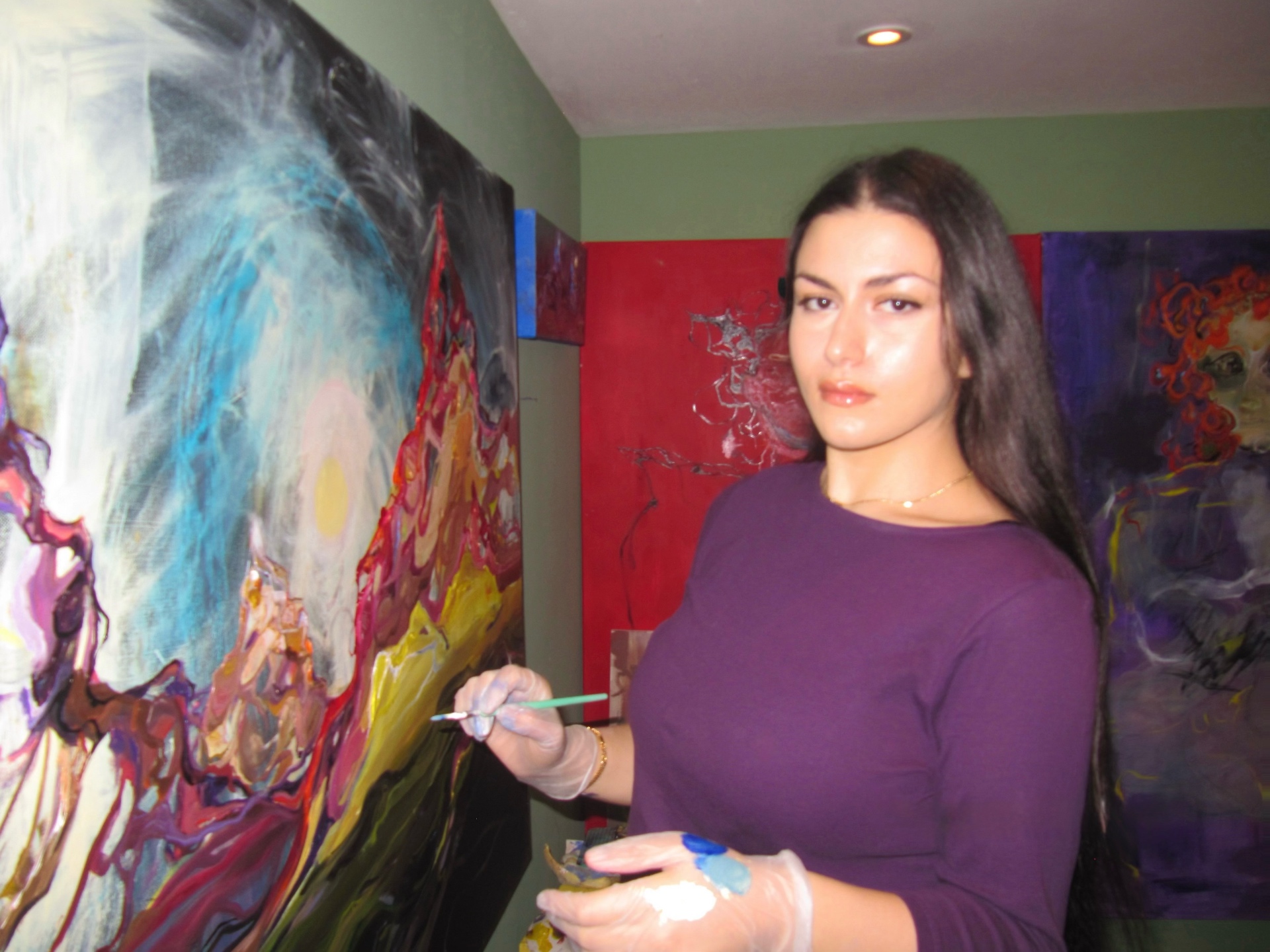 Diyara, the artist behind Passionflowwer, painting a large canvas in her studio.